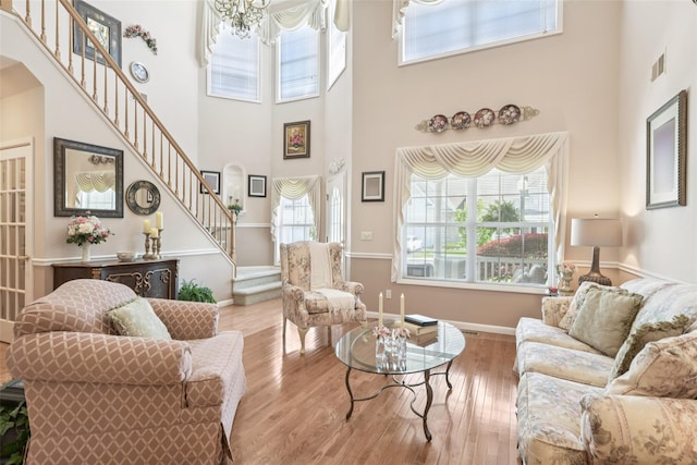 17 Meadow Pond Cir, Miller Place, NY 11764 - living room featuring stairs, a towering ceiling, wood finished floors, arched walkways, and a chandelier
