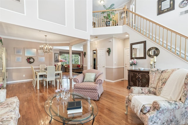 17 Meadow Pond Cir, Miller Place, NY 11764 - living room featuring ornamental molding, a chandelier, light wood-style floors, decorative columns, and stairs