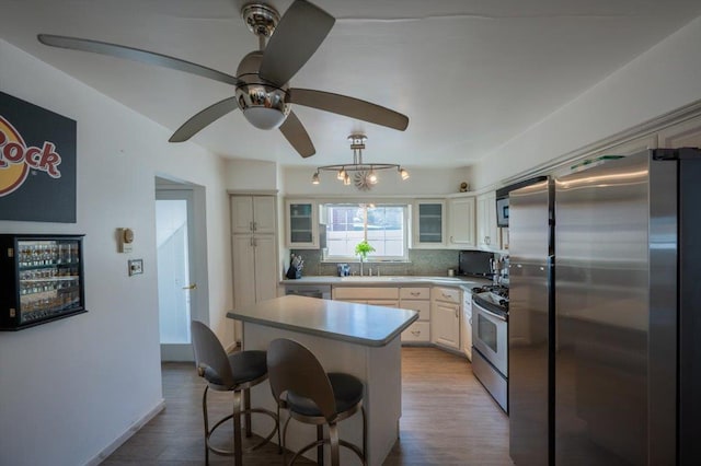 19611 Pompeii Ave, Hollis, NY 11423 - kitchen with stainless steel appliances, decorative backsplash, a kitchen bar, a kitchen island, and light wood-style floors