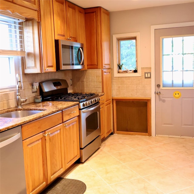 24 Pine St, Oceanside, NY 11572 - kitchen with stainless steel appliances, light stone counters, brown cabinetry, tasteful backsplash, and light tile patterned flooring