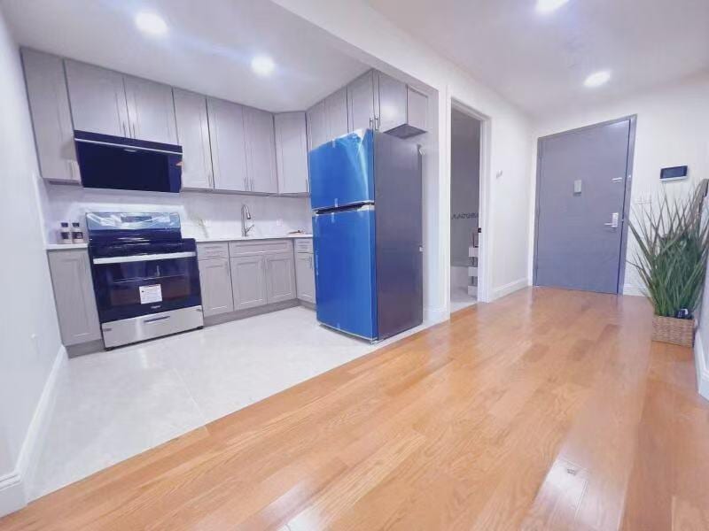 141-15 Cherry Ave Unit 2E, Flushing, NY 11355 - kitchen with freestanding refrigerator, electric stove, gray cabinets, extractor fan, and light countertops