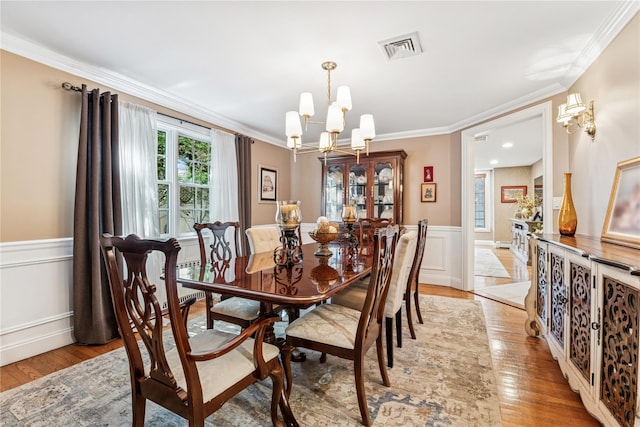 42 Roxen Rd, Rockville Centre, NY 11570 - dining area with a chandelier, wainscoting, light wood-style flooring, crown molding, and a decorative wall