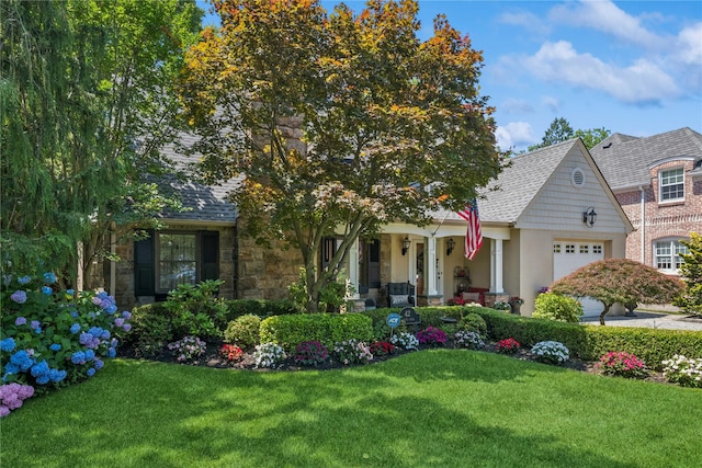 42 Roxen Rd, Rockville Centre, NY 11570 - view of front of property featuring a garage, a front yard, stone siding, and covered porch