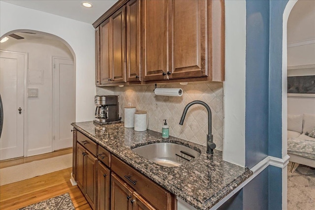 104 S Village Ave S Unit 1F, Rockville Centre, NY 11570 - kitchen with arched walkways, backsplash, dark stone countertops, light wood-style floors, and recessed lighting