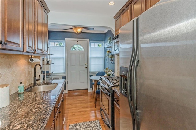 104 S Village Ave S Unit 1F, Rockville Centre, NY 11570 - kitchen featuring stainless steel appliances, decorative backsplash, light wood-style flooring, ceiling fan, and dark stone counters