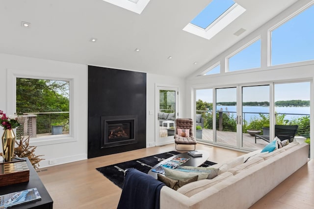 55C Shore Rd, Shelter Island, NY 11964 - living area with a skylight, a large fireplace, wood finished floors, a water view, and high vaulted ceiling