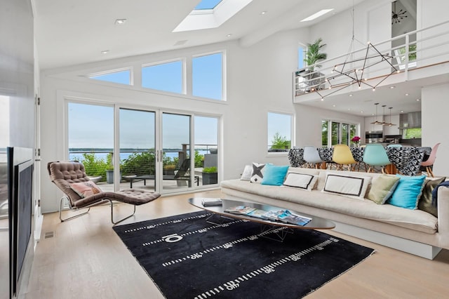55C Shore Rd, Shelter Island, NY 11964 - living room featuring a chandelier, wood finished floors, a high ceiling, a skylight, and a water view