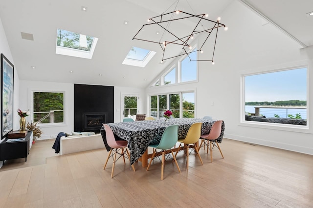 55C Shore Rd, Shelter Island, NY 11964 - dining area featuring high vaulted ceiling, light wood-type flooring, a skylight, and a glass covered fireplace