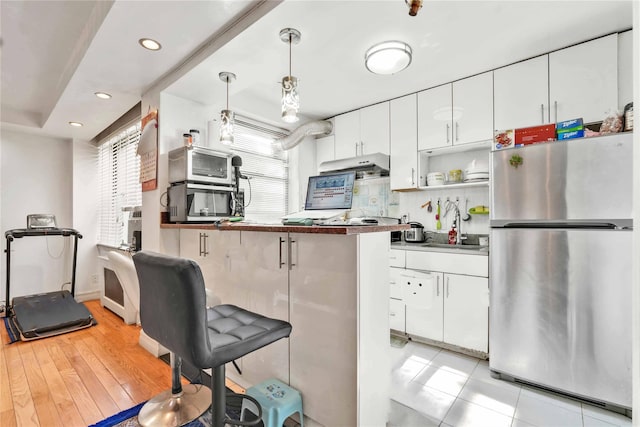141-15 28th Ave Unit 1G, Flushing, NY 11354 - kitchen featuring freestanding refrigerator, white cabinetry, recessed lighting, a kitchen breakfast bar, and a peninsula
