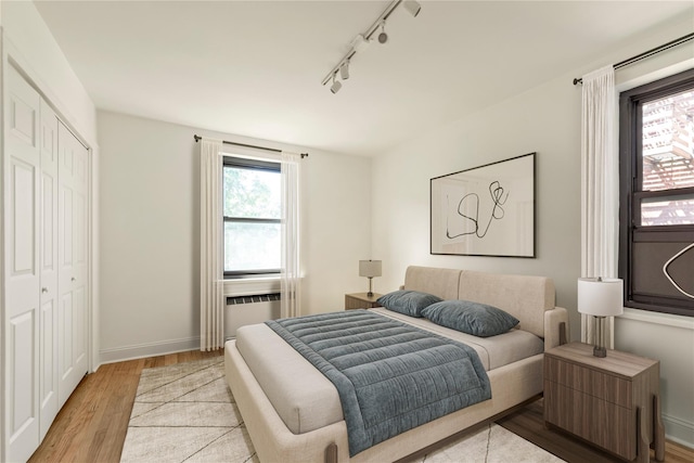 212-04 75th Ave Unit 4J, Bayside, NY 11364 - bedroom featuring rail lighting, radiator, a closet, and light wood-type flooring