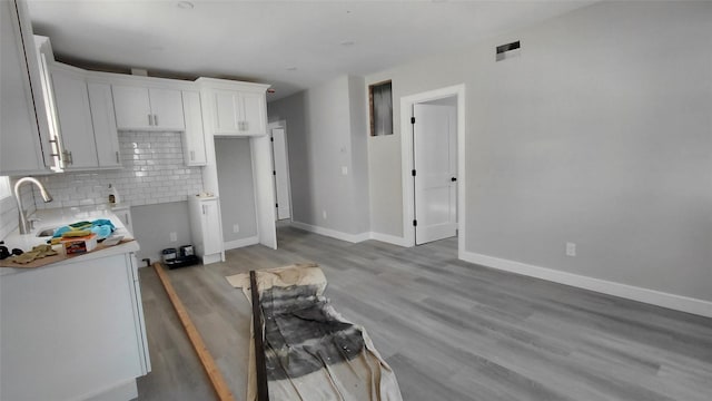117-36 165th St, Jamaica, NY 11434 - kitchen with decorative backsplash, light wood finished floors, white cabinets, and light countertops