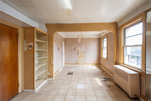 31-30 100th St, East Elmhurst, NY 11369 - unfurnished room with radiator heating unit, arched walkways, and light tile patterned floors