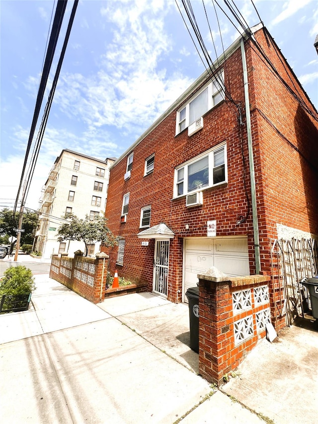 40-03 56th St, Woodside, NY 11377 - view of property featuring a garage, cooling unit, and driveway