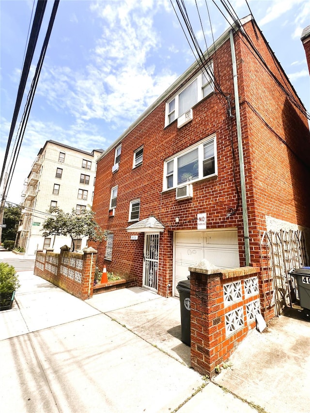 40-03 56th St, Woodside, NY 11377 - view of building exterior featuring a garage, driveway, and cooling unit