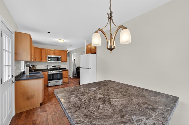 15 Claremont Trl, Monroe, NY 10950 - kitchen with appliances with stainless steel finishes, dark countertops, wood finished floors, decorative light fixtures, and brown cabinetry