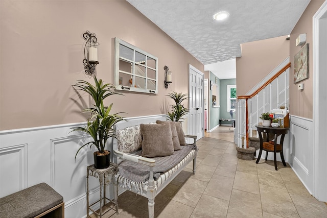 8 Argow Pl, Nanuet, NY 10954 - entrance foyer with wainscoting, a decorative wall, a textured ceiling, stairway, and light tile patterned floors