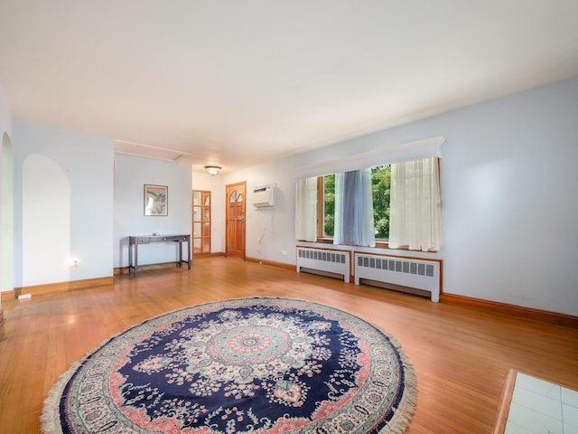 19 E Orchard St, Nanuet, NY 10954 - living room with radiator heating unit, a wall mounted AC, wood finished floors, and arched walkways