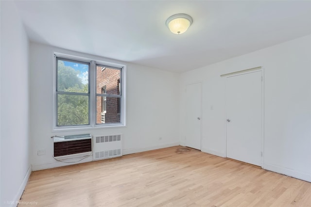46-01 39th Ave Unit 303, Sunnyside, NY 11104 - unfurnished bedroom with radiator heating unit, light wood finished floors, and a wall mounted air conditioner