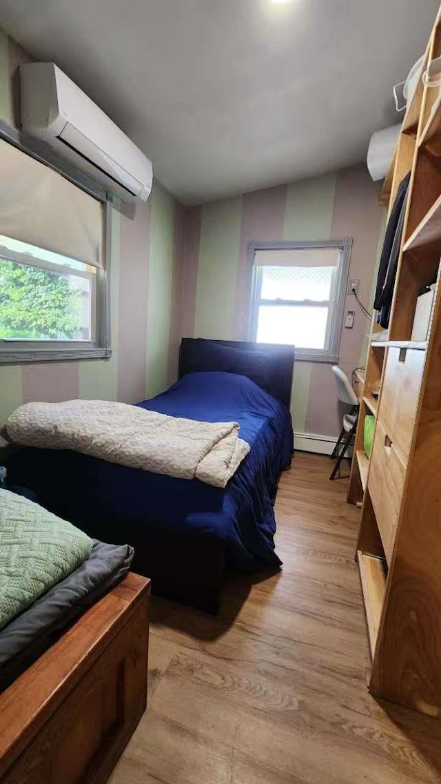 9-24 College Point Blvd, College Point, NY 11356 - bedroom with an AC wall unit, light wood finished floors, multiple windows, and a baseboard radiator