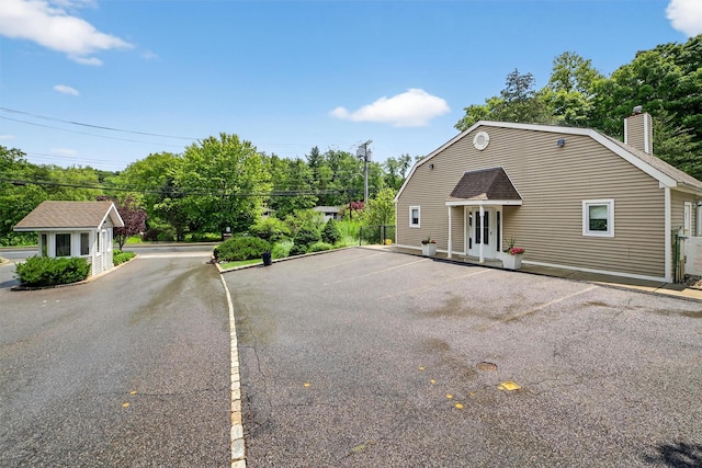 32 Spring Pond Dr, Ossining, NY 10562 - view of front of home with a gambrel roof, uncovered parking, a chimney, and an outbuilding