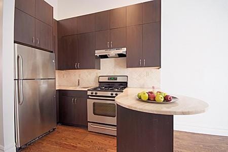 235 W 120th St, New York Manhattan, NY 10027 - kitchen featuring appliances with stainless steel finishes, range hood, light countertops, a peninsula, and backsplash