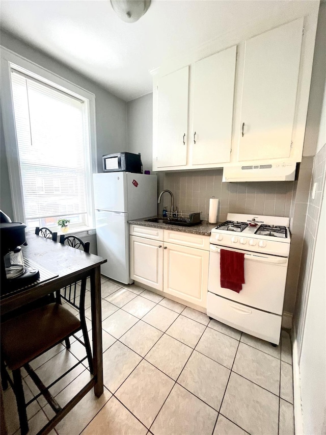 7863 79th Ln, Glendale, NY 11385 - kitchen featuring white appliances, under cabinet range hood, decorative backsplash, dark countertops, and light tile patterned flooring