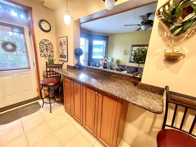 7863 79th Ln, Glendale, NY 11385 - kitchen featuring brown cabinets, light tile patterned floors, ceiling fan, pendant lighting, and a peninsula