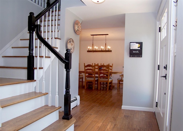 71 Strathmore Village Dr, South Setauket, NY 11720 - foyer entrance with stairs, wood finished floors, a chandelier, and a baseboard radiator