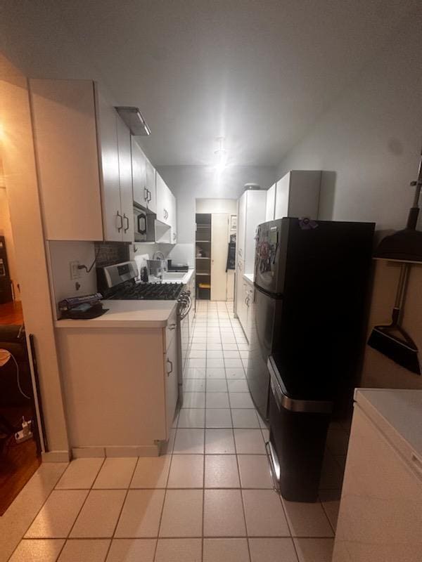 141 Wyckoff Pl Unit 1F, Woodmere, NY 11598 - kitchen featuring stainless steel range with gas stovetop, black microwave, light countertops, freestanding refrigerator, and light tile patterned floors