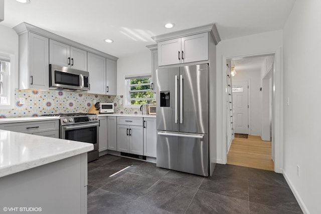 65 Union St, Beacon, NY 12508 - kitchen featuring appliances with stainless steel finishes, decorative backsplash, gray cabinetry, recessed lighting, and light stone counters