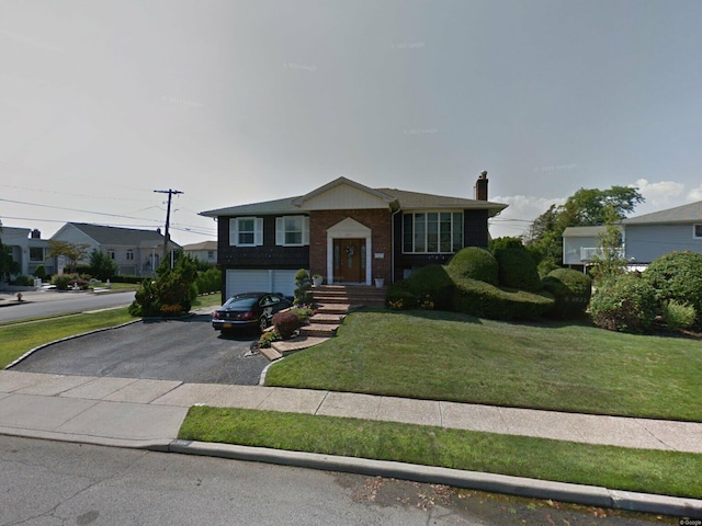 3214 Monterey Dr, Merrick, NY 11566 - split foyer home with driveway, an attached garage, a chimney, a front lawn, and brick siding