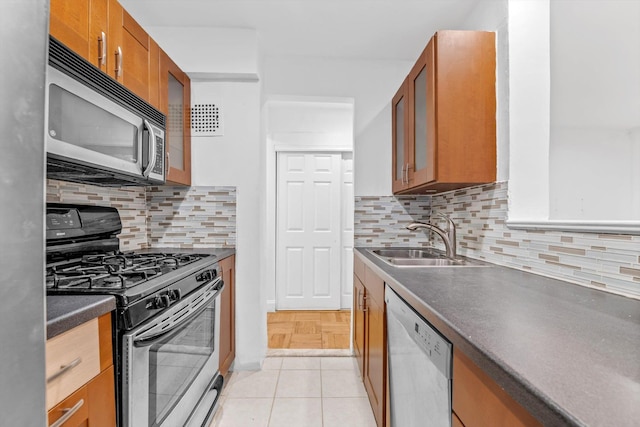 5425 Valles Ave Unit 1L, Bronx, NY 10471 - kitchen with stainless steel appliances, brown cabinetry, dark countertops, glass insert cabinets, and decorative backsplash