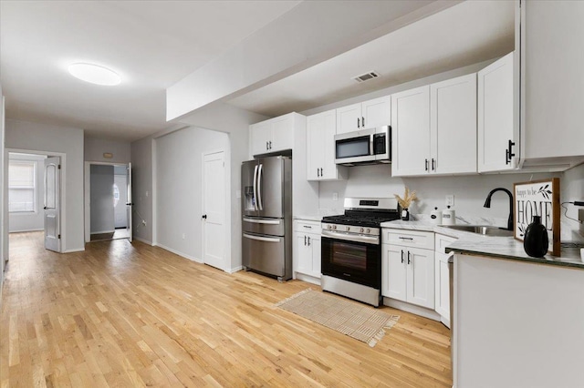 748 Georgia Ave, Brooklyn, NY 11207 - kitchen with appliances with stainless steel finishes, light wood-style floors, and white cabinets