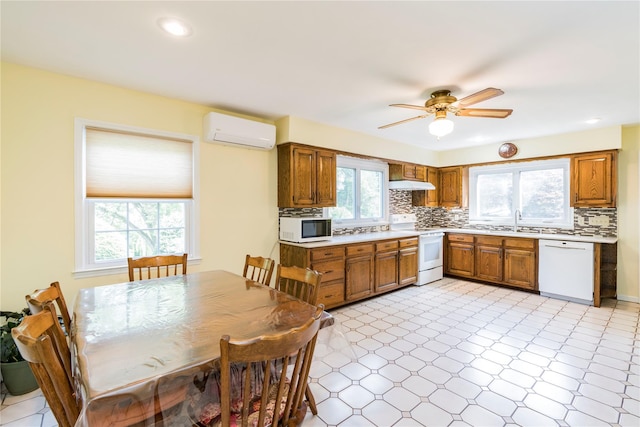 4 Pasture Ln, Poughkeepsie, NY 12603 - kitchen featuring white appliances, a wall mounted air conditioner, under cabinet range hood, light countertops, and brown cabinets
