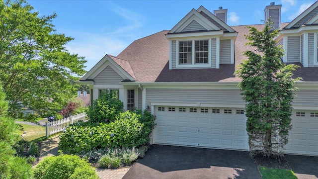 18 Tall Tree Cir, Jamesport, NY 11901 - view of front facade with driveway, roof with shingles, a chimney, and an attached garage