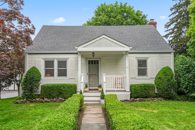 42 Valley Ave, Locust Valley, NY 11560 - view of front facade with a front yard, a chimney, and a shingled roof