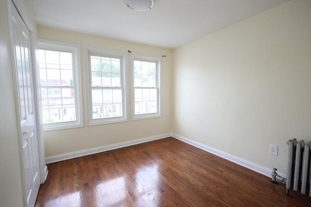 10416 Rosita Rd, Ozone Park, NY 11417 - unfurnished room featuring radiator and dark wood-style flooring