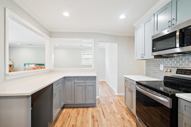 1126 Park Blvd, Massapequa Park, NY 11762 - kitchen with appliances with stainless steel finishes, gray cabinetry, tasteful backsplash, light wood-type flooring, and light countertops