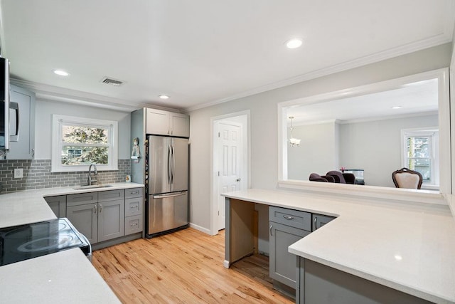 1126 Park Blvd, Massapequa Park, NY 11762 - kitchen with freestanding refrigerator, gray cabinetry, light wood-style floors, ornamental molding, and light countertops