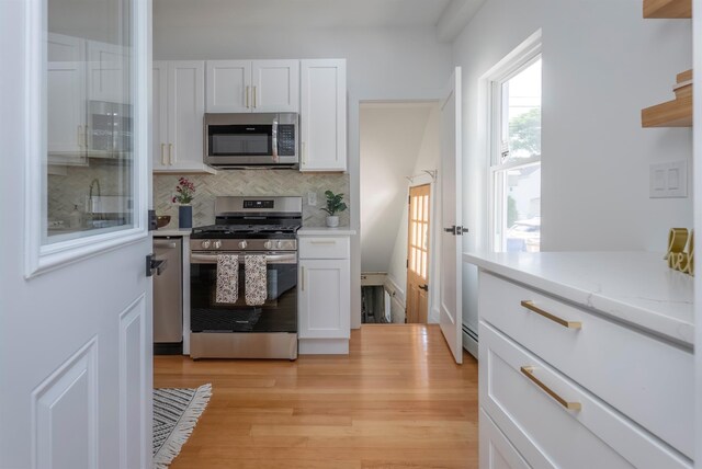 14 Staples St, Kingston, NY 12401 - kitchen with stainless steel appliances, white cabinetry, backsplash, and light wood-style flooring