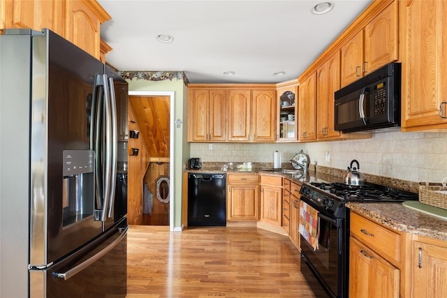 7 Garnet Ln, Plainview, NY 11803 - kitchen featuring black appliances, glass insert cabinets, light wood-style floors, dark stone countertops, and tasteful backsplash