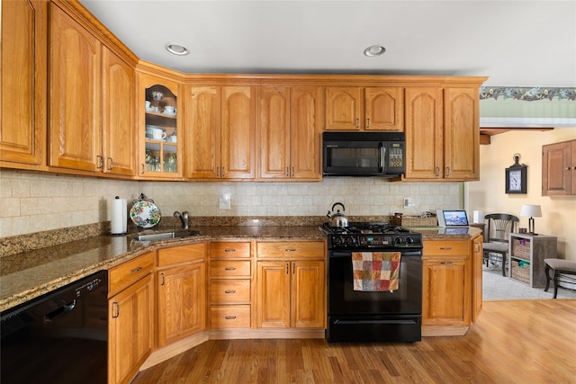 7 Garnet Ln, Plainview, NY 11803 - kitchen featuring black appliances, dark stone counters, glass insert cabinets, wood finished floors, and brown cabinetry