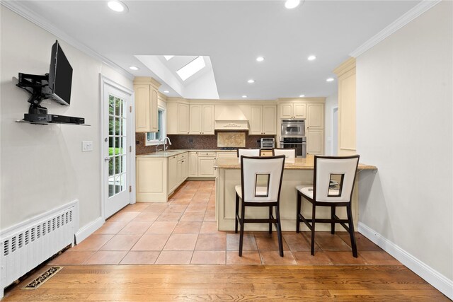 156 Lefferts Rd, Woodmere, NY 11598 - kitchen featuring radiator heating unit, cream cabinets, premium range hood, a skylight, and ornamental molding