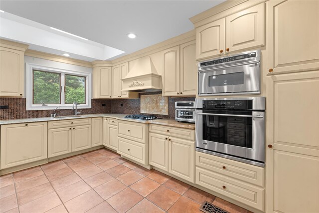 156 Lefferts Rd, Woodmere, NY 11598 - kitchen with cream cabinets, custom range hood, backsplash, light tile patterned floors, and stainless steel appliances