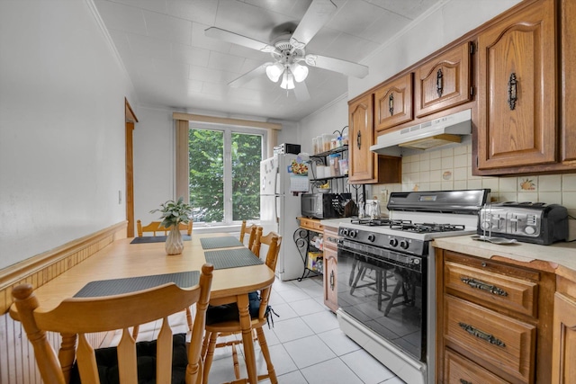 6303 74th St, Middle Village, NY 11379 - kitchen featuring white appliances, under cabinet range hood, brown cabinets, a ceiling fan, and backsplash