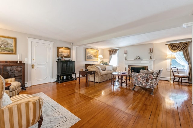 107 S Country Rd, East Patchogue, NY 11772 - living area with a fireplace, a baseboard radiator, hardwood / wood-style flooring, and a wood stove