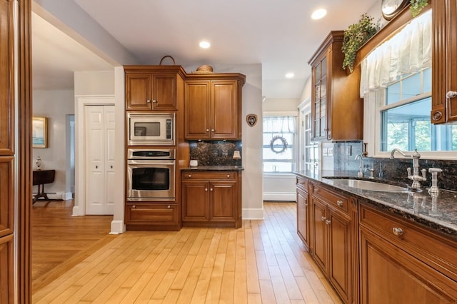 107 S Country Rd, East Patchogue, NY 11772 - kitchen featuring appliances with stainless steel finishes, light wood finished floors, dark stone countertops, tasteful backsplash, and healthy amount of natural light