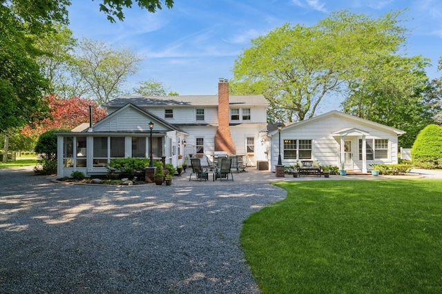 107 S Country Rd, East Patchogue, NY 11772 - rear view of property with a sunroom, a patio area, a yard, and a chimney