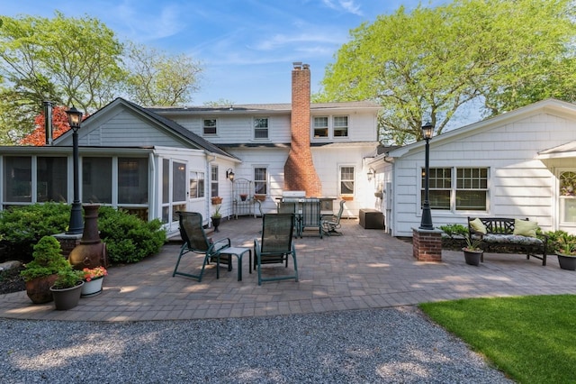 107 S Country Rd, East Patchogue, NY 11772 - rear view of property featuring a chimney, a patio, a sunroom, and outdoor dining area