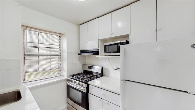 144-37 79th Ave Unit 1R, Kew Garden Hills, NY 11367 - kitchen with appliances with stainless steel finishes, under cabinet range hood, white cabinetry, and backsplash